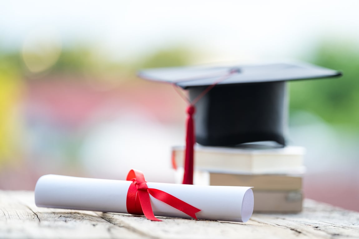 Graduation Cap with Diploma over Piled Books Copy Space